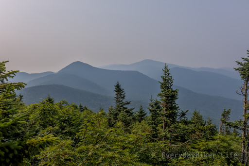 Looking eastward from the summit of Mt Mansfield. A range of mountains unfolds in the smoky haze, with Madonna Peak in the center and Morse mountain and the taller Whiteface mountain on the left.
